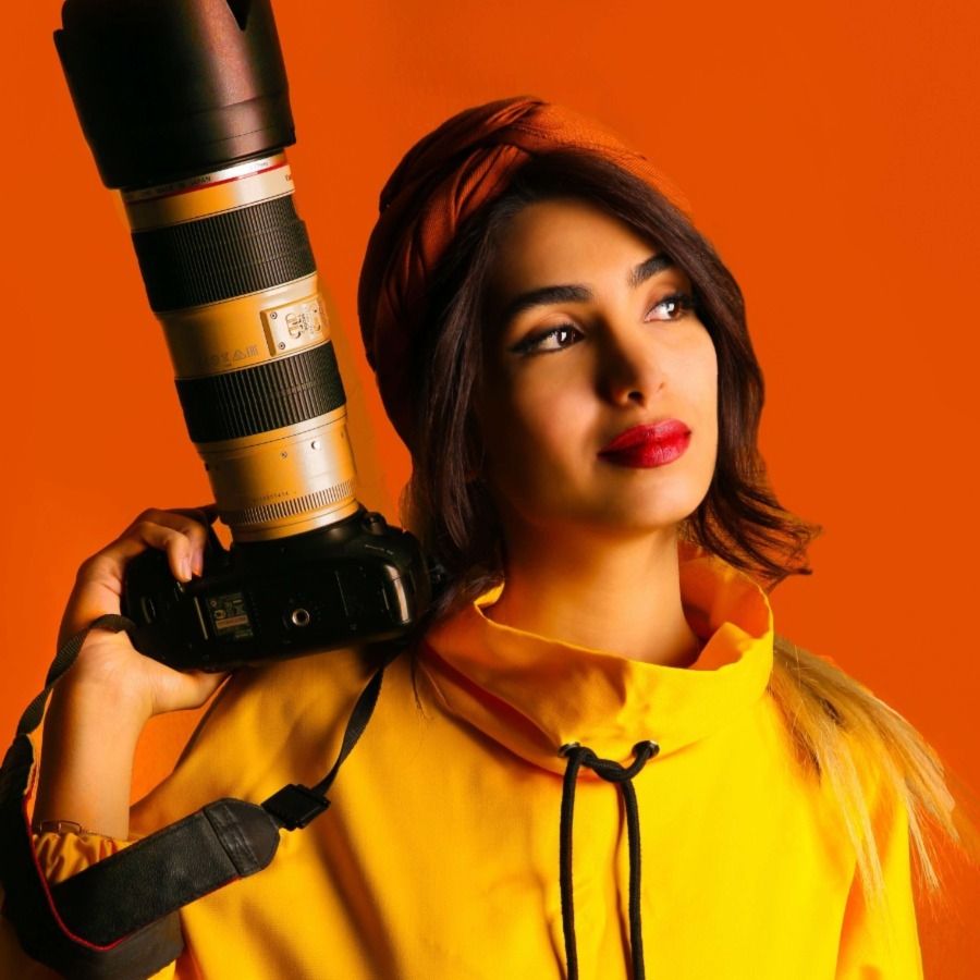 Fotograf mody z aparatem w pomarańczowym tle